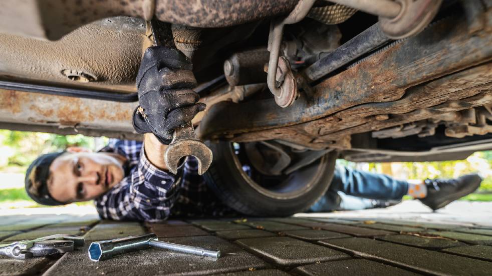 Car maintenance checklist car repairs man fixing underside of car